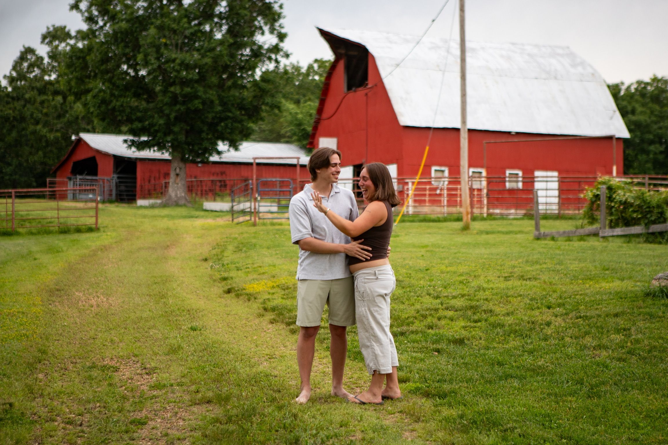 Andrew and Grace holding each other on a grassy path in front of a red barn