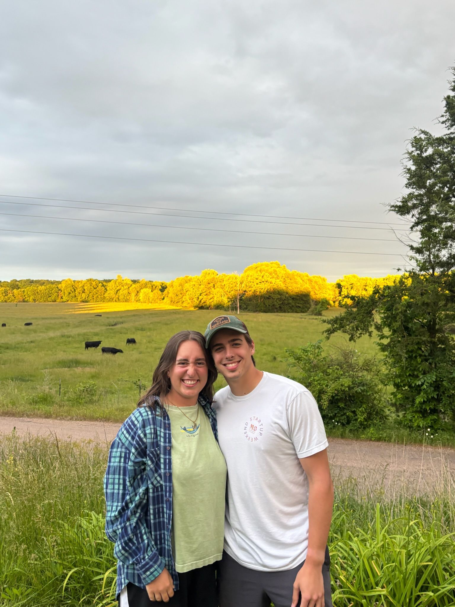 Andrew and Grace standing by a green field in evening light