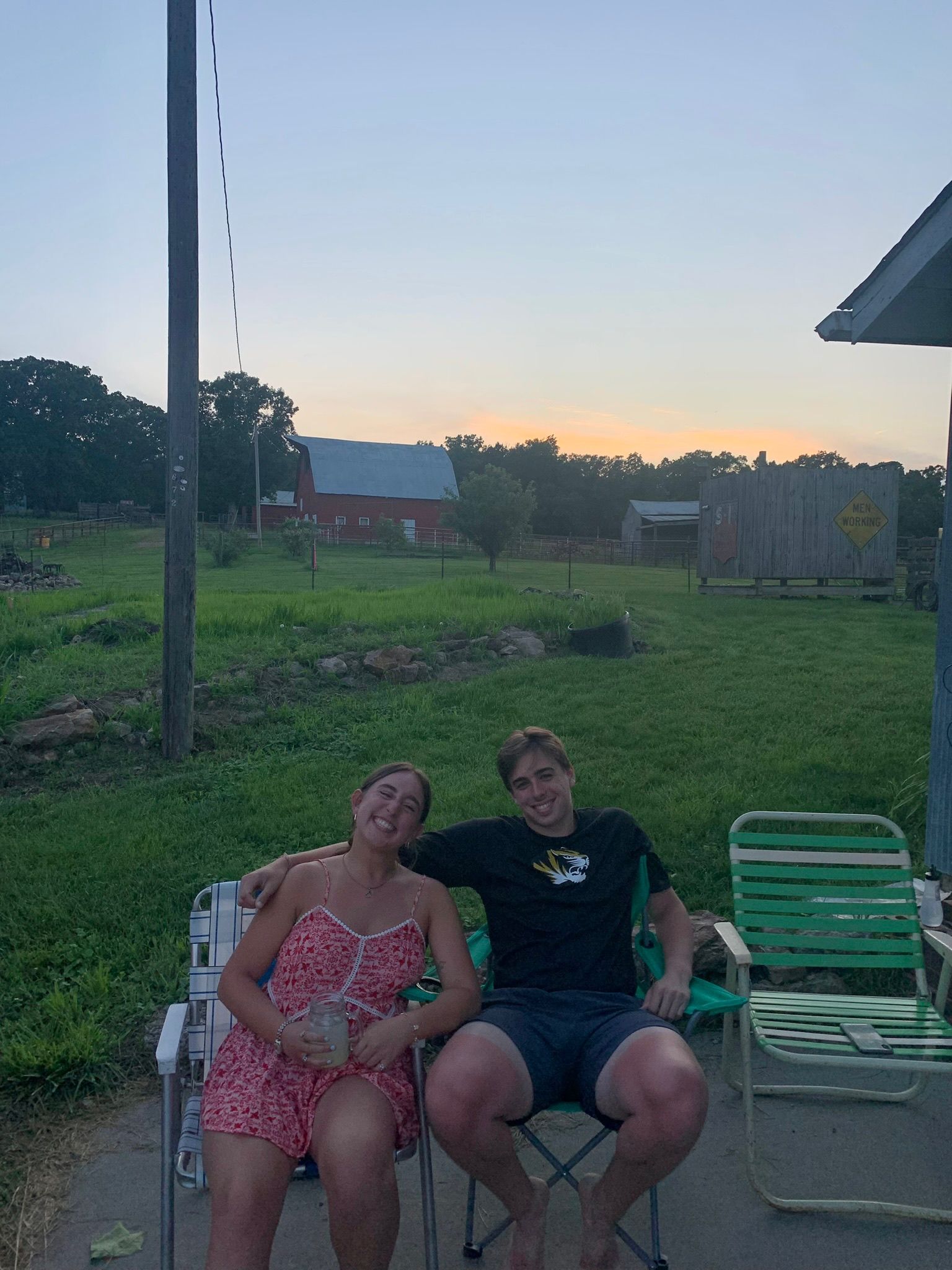 Andrew and Grace sitting in lawn chairs on a farm at sunset