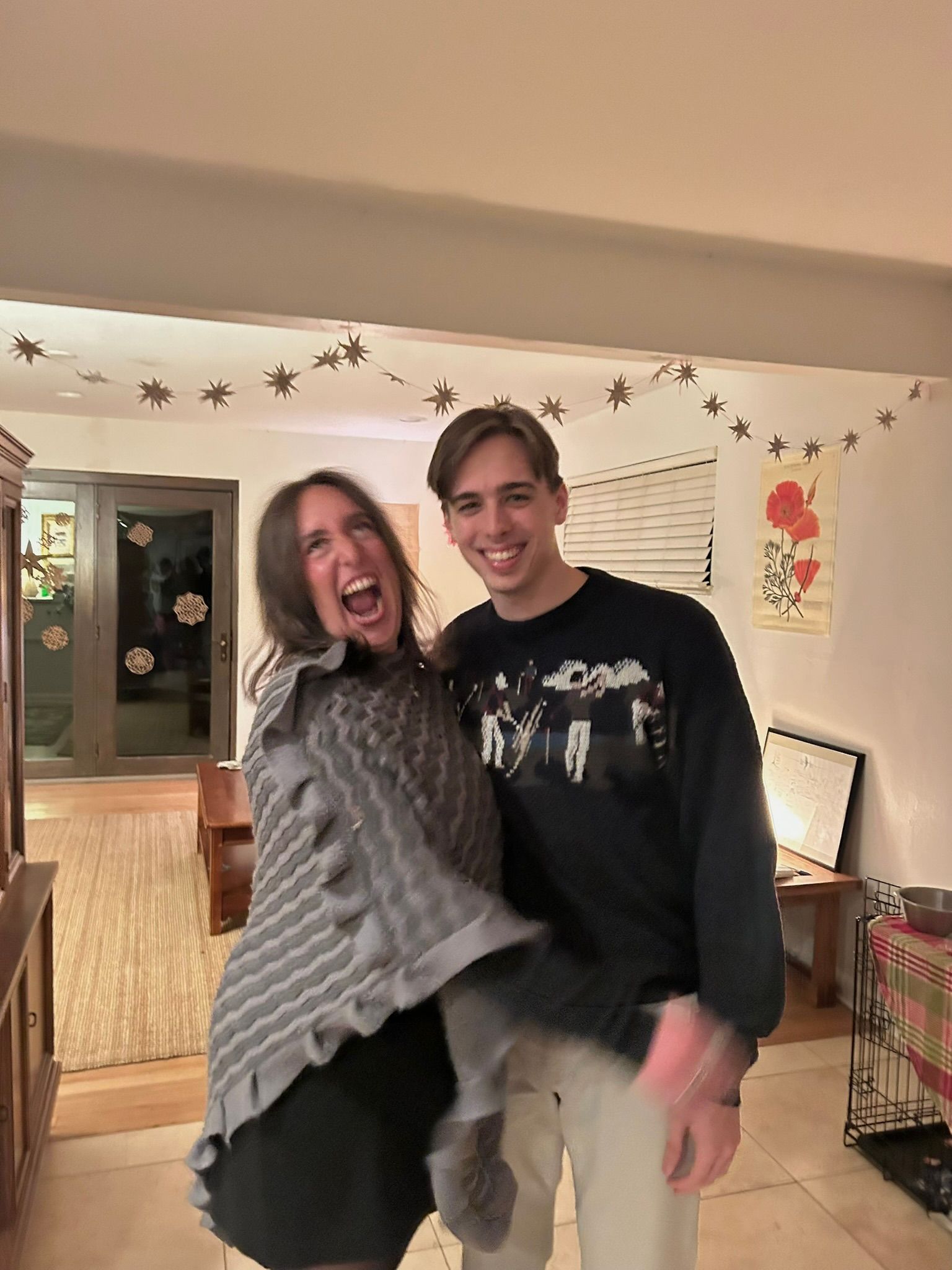 Andrew and Grace laughing in a living room strung with paper stars