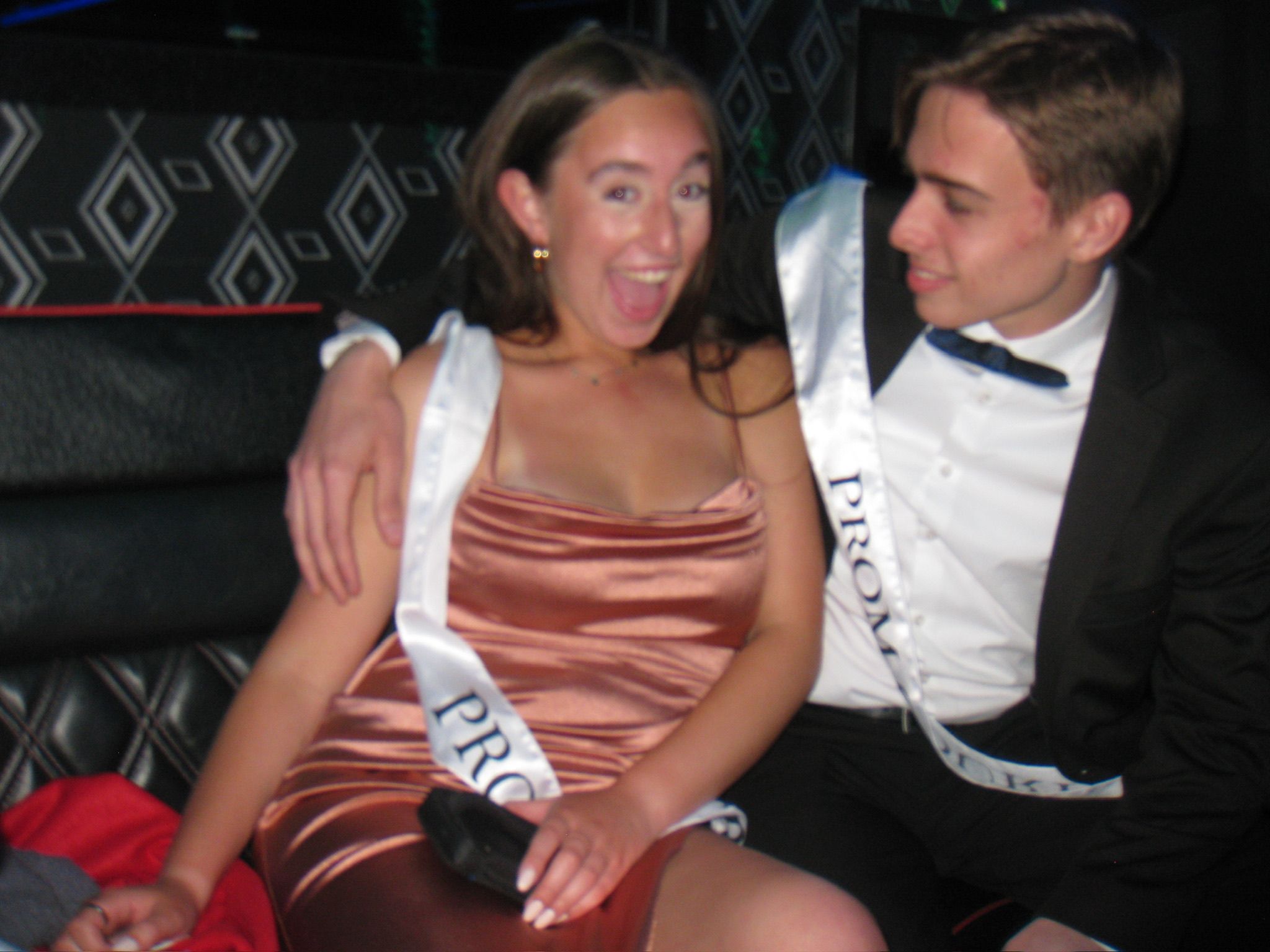 Andrew and Grace dressed up and wearing sashes, Grace laughing