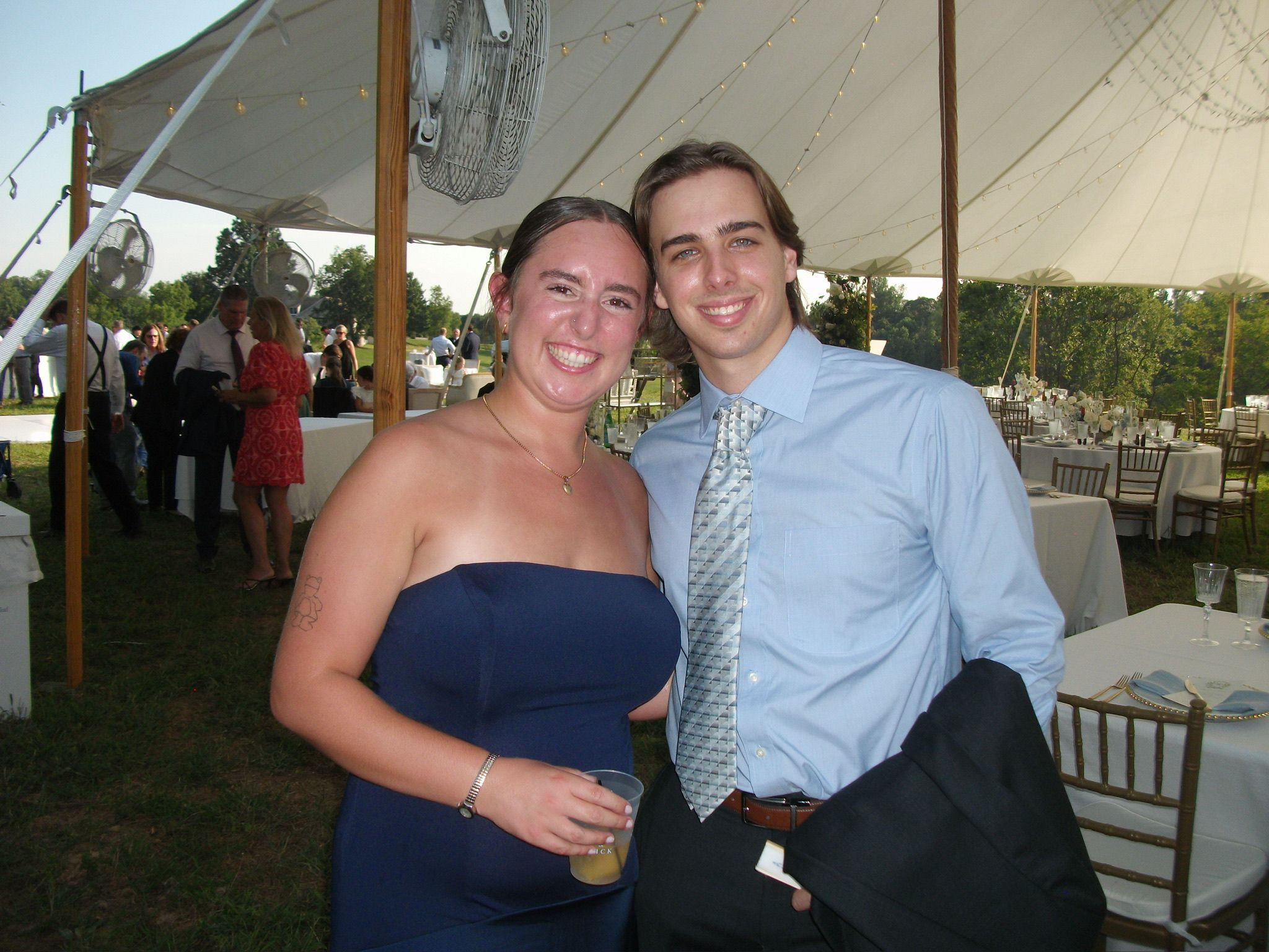 Andrew and Grace dressed up under a white tent at an outdoor party